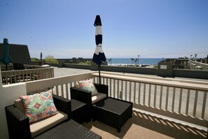 A rooftop terrace with outdoor furniture, a view of the ocean, and a clear sky. - B306 - Luxury Penthouse with spacious deck. Enjoy ocean View from Deck lounge sun bed (Oceanside)
