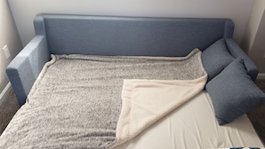 A room with a blue sofa, a white pillow, and a grey blanket. - B306 - Luxury Penthouse with spacious deck. Enjoy ocean View from Deck lounge sun bed (Oceanside)