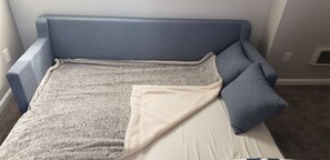 A room with a blue sofa, a white pillow, and a grey blanket. - B306 - Luxury Penthouse with spacious deck. Enjoy ocean View from Deck lounge sun bed (Oceanside)