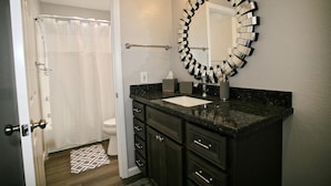 A bathroom with a dark marble sink, a mirror with a unique design, and a white toilet. - B306 - Luxury Penthouse with spacious deck. Enjoy ocean View from Deck lounge sun bed (Oceanside)