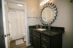 A bathroom with a dark marble sink, a mirror with a unique design, and a white toilet. - B306 - Luxury Penthouse with spacious deck. Enjoy ocean View from Deck lounge sun bed (Oceanside)