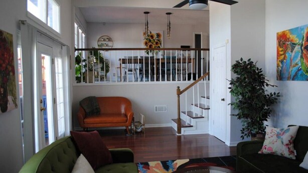 A spacious living room with a green sofa, a brown leather couch, and a black sofa. There is a staircase with a wooden railing leading to an upper level. - Spacious, beautifully designed, spectacular views, awesome pool. (Nashville)