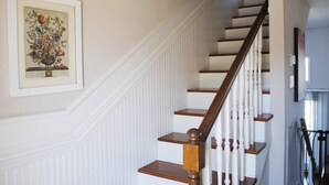 A staircase with white railings and wooden steps, leading to a landing with a framed botanical print on the wall. - Spacious, beautifully designed, spectacular views, awesome pool. (Nashville)