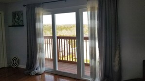 A room with a sliding glass door leading to a deck, wooden flooring, and a painting on the wall. - Spacious, beautifully designed, spectacular views, awesome pool. (Nashville)