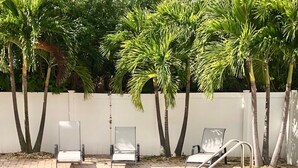 A swimming pool with lounge chairs and palm trees. - A Perfect Condo Near The Beach - just renovated! (St Pete Beach)
