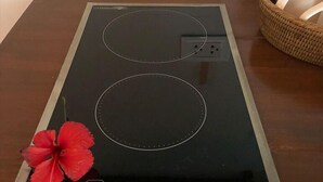 A black induction cooktop with two circular cooking surfaces and a control panel with various buttons. - Sadhana Siargao (General Luna)