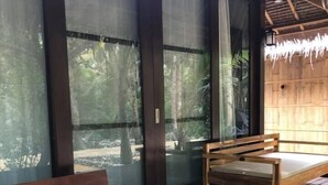A wooden deck with a sofa, a table with a floral centerpiece, and a bench. - Sadhana Siargao (General Luna)