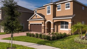 A two-story residential building with a garage, a small porch, and a well-maintained lawn. - Encore Resort at Reunion 1866 (Kissimmee)