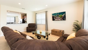 A living room with a sofa set, a glass coffee table, a wooden chest, and a painting on the wall. - Encore Resort at Reunion 1866 (Kissimmee)