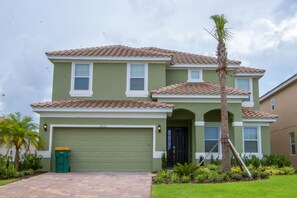 A two-story house with a green facade, a brown tiled roof, and a garage. - Golden Palms Vacation Resort 1847 (Kissimmee)
