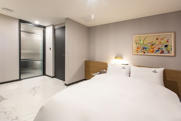 Una habitación de hotel con una cama grande, cabecera de madera, un cuadro en la pared y una puerta corredera.