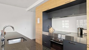 A modern kitchen with a stainless steel sink, a built-in oven, and a coffee maker.