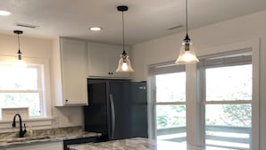 A modern kitchen with white cabinets, a marble countertop, and a central island with bar stools.