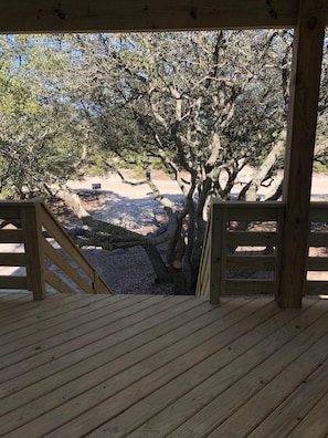 Enjoy a serene view from this outdoor deck overlooking a natural landscape with a large tree and sandy area.