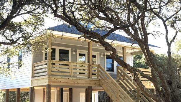 A wooden deck with a staircase leading to a house with a blue roof.
