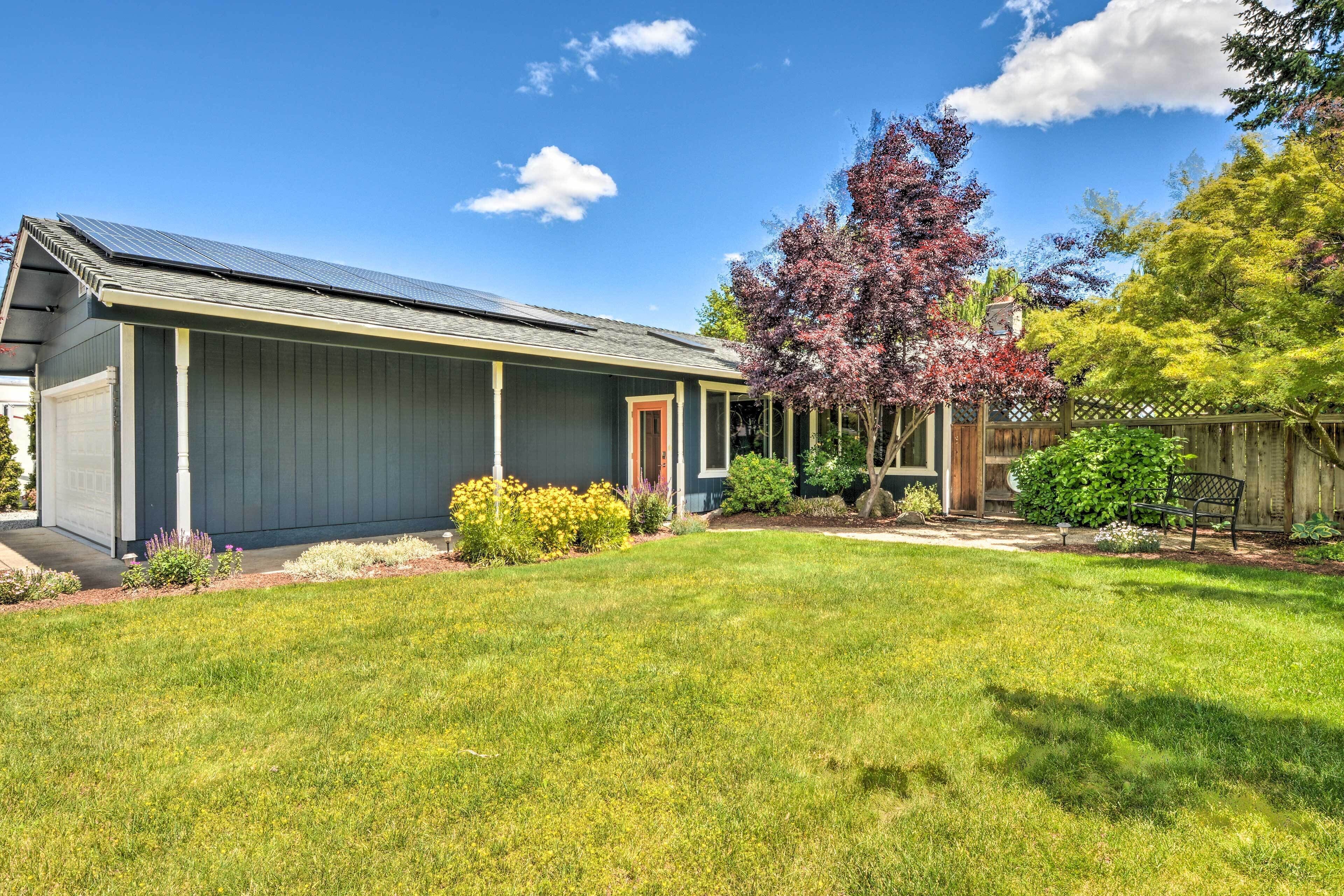 A residential house with a covered porch, a well-maintained lawn, and a variety of flowering plants.