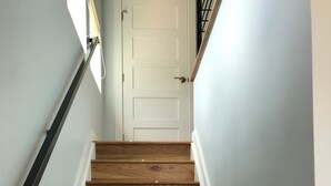 A wooden staircase with white walls and a white door at the top.