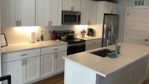A modern kitchen with white cabinets, stainless steel appliances, and a central island.
