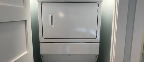 Una unidad compacta de lavadora y secadora Whirlpool blanca en un pasillo estrecho.