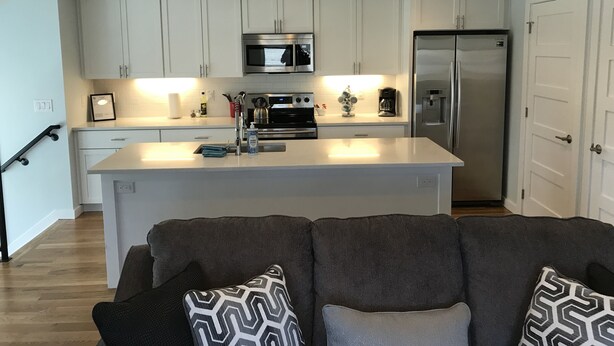 A modern kitchen with white cabinets, stainless steel appliances, and a central island.