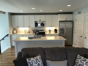 A modern kitchen with white cabinets, stainless steel appliances, and a central island. - Private Residence in Berkeley (Denver)