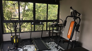 Et fitnessrum med træningsudstyr, løbebånd og bænk.