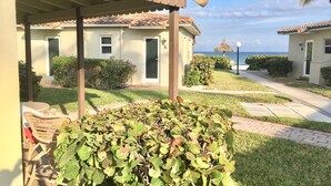 Ein Resort mit überdachter Außenbereich-Sitzgelegenheit, einem gepflegten Rasen und Blick auf den Ozean.