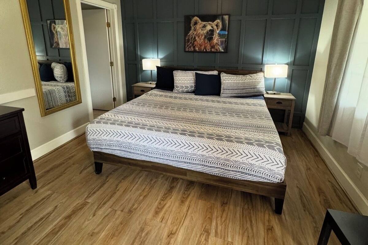 Ein Schlafzimmer mit einem großen Bett, einem Deckenventilator, einem Spiegel und einem Wandbild.