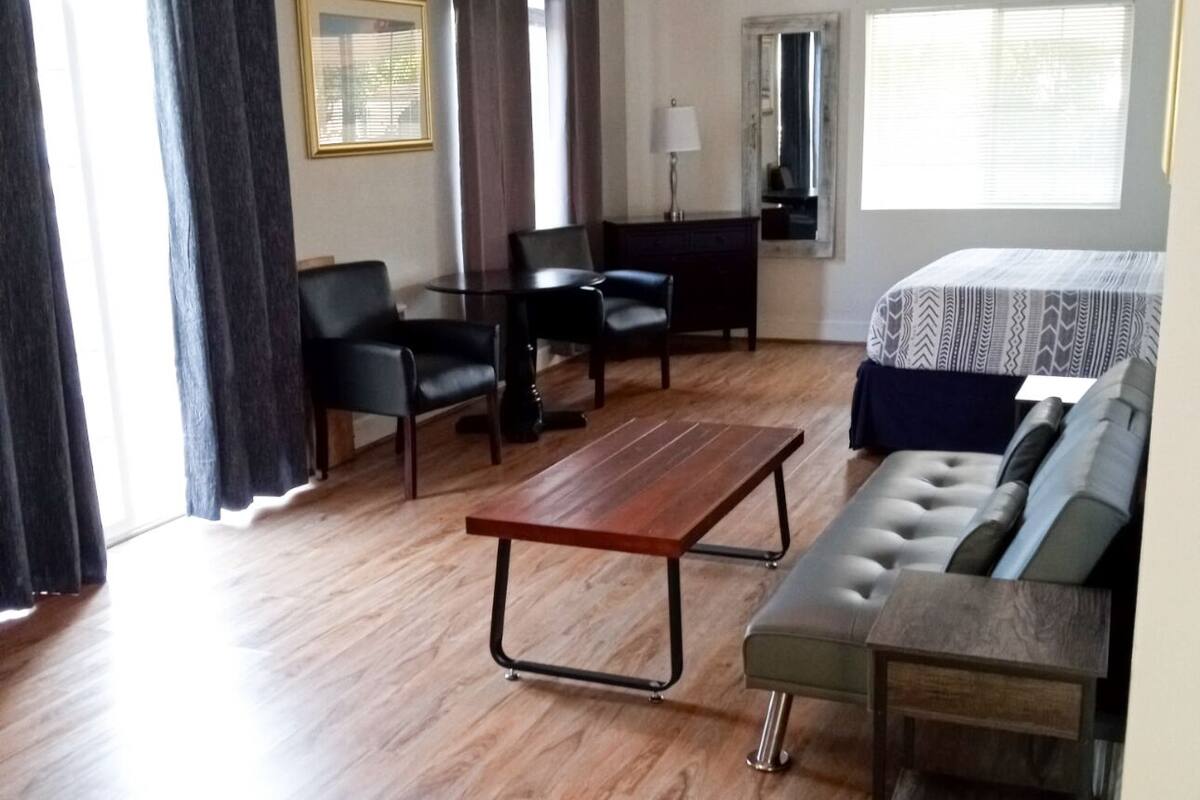 Ein Zimmer mit Holzboden, einer Couch, einem Tisch und einem Deckenventilator.