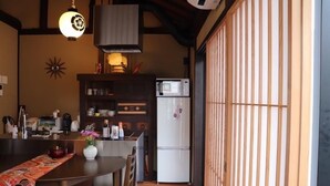 Une cuisine compacte avec un coin repas, équipée d’un four à micro-ondes, d’un réfrigérateur et de meubles de rangement en bois.