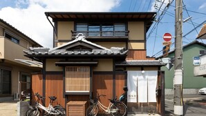 Un bâtiment japonais traditionnel, avec un toit recouvert de tuiles, une façade en bois et un petit balcon.
