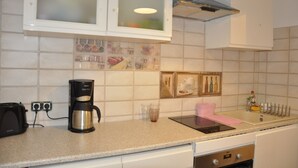 Een keuken met witte kastjes, een koffiezetapparaat, een broodrooster en een gootsteen.