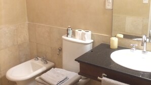 Ein Badezimmer mit Bidet, Toilette, Waschbecken und Spiegel.