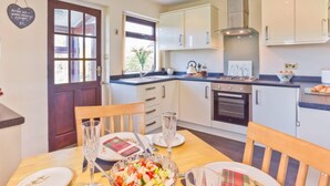 Una cocina moderna con armarios blancos, una estufa y un comedor con una mesa dispuesta para dos personas.