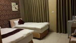 A hotel room with two beds, a desk with a chair, and a curtain. - Hilarity B&B (Hualien City)