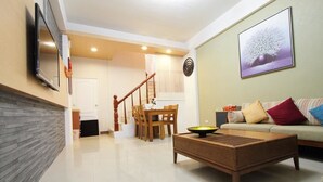 A living room with a sofa, coffee table, and a TV mounted on the wall. - Hilarity B&B (Hualien City)