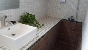 A bathroom with a white sink, a mirror, and a shower area. - Hilarity B&B (Hualien City)