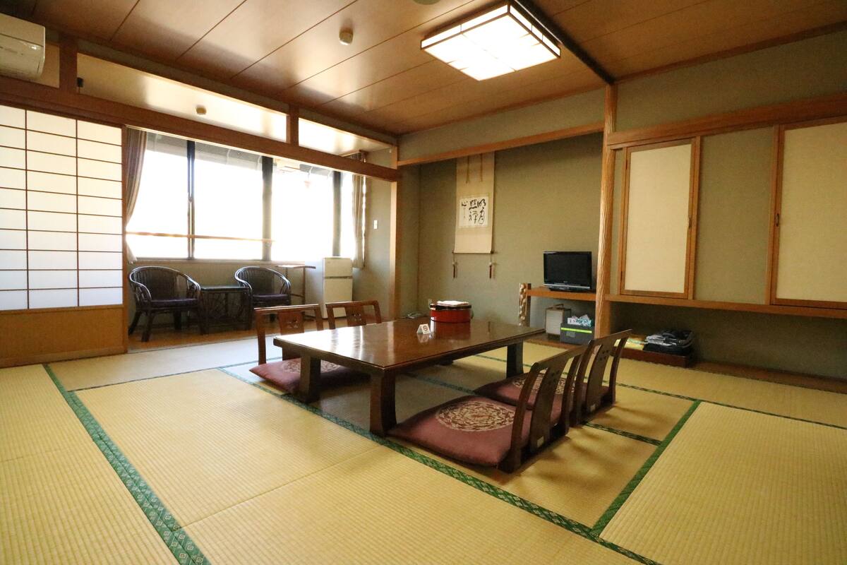 A traditional Japanese room with tatami flooring, a low table with cushions, and sliding doors.