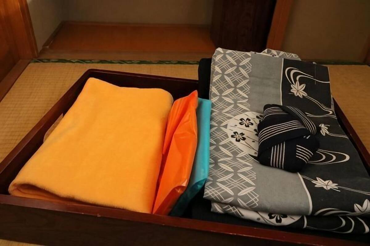 A traditional Japanese futon bed with a wooden frame, a tatami mat floor, and a small wooden stool.