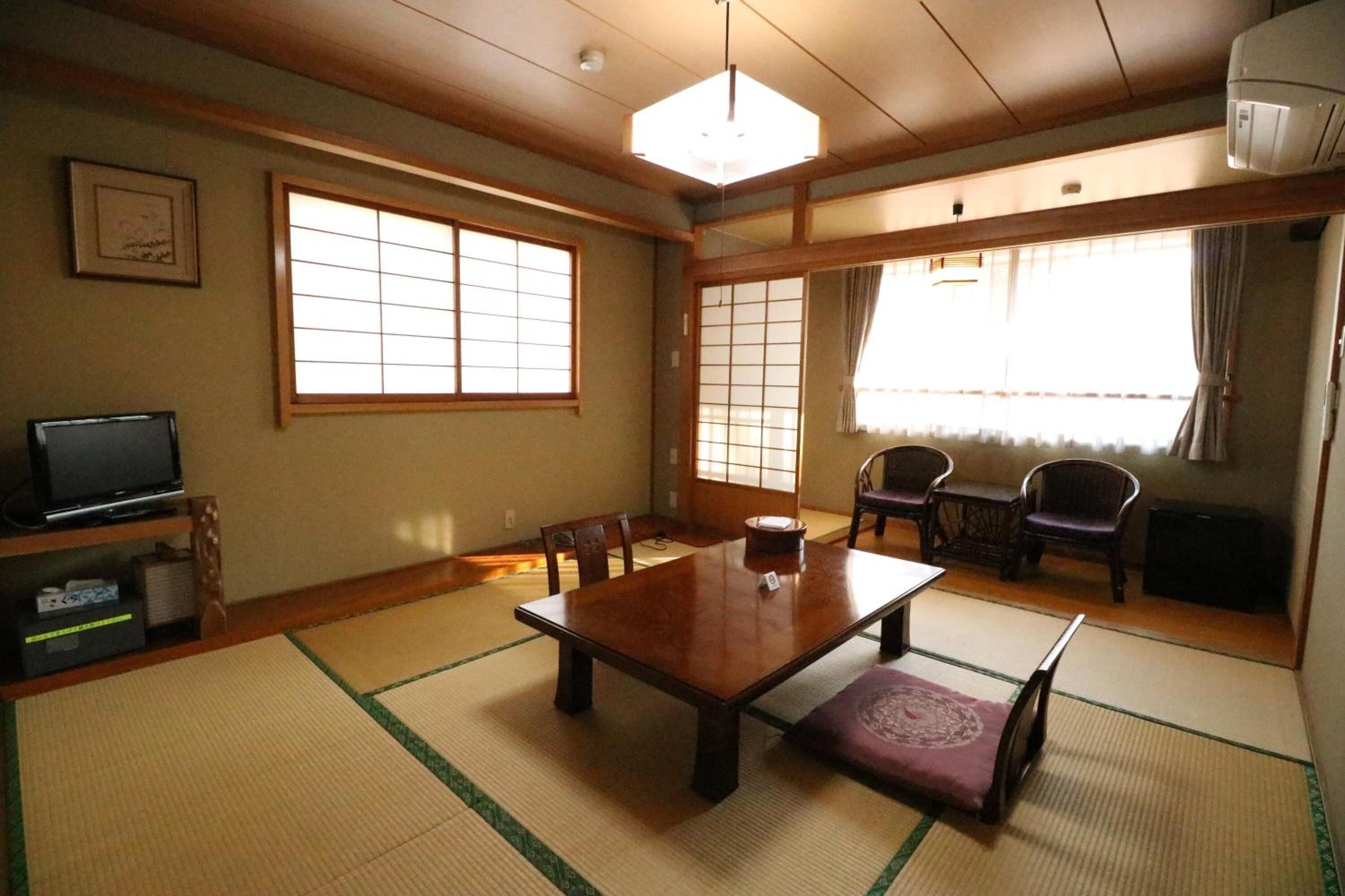 A traditional Japanese-style room with tatami flooring, a wooden table, and sliding doors.