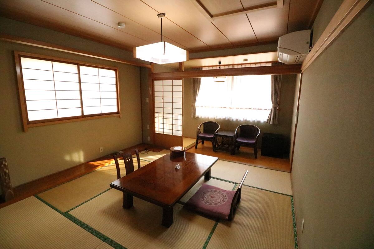 A traditional Japanese room with tatami flooring, a wooden table, and sliding doors.