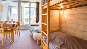 Et hyggeligt værelse med køjesenge, et spiseområde med stole og et bord, og et stort vindue med udsigt.