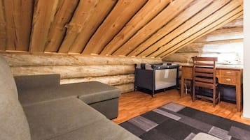 Une pièce mansardée chaleureuse avec un plafond en bois, un canapé, un fauteuil et un petit bureau.