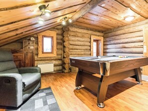 A cozy log cabin with a pool table, a comfortable chair, and a small window. - Eräkorven kelotupa by Interhome (Pielavesi)