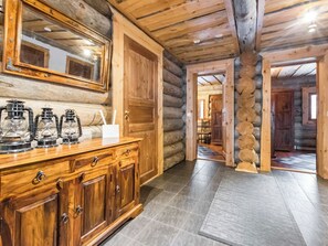 A wooden cabin interior with a large mirror, a wooden cabinet with glass jars, and a log wall.