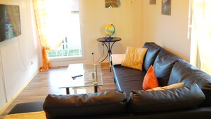 A living room with a black leather sofa, a glass coffee table, and a small round table with a globe.