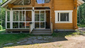Une cabane en bois à deux étages, dotée de grandes fenêtres et d’un balcon.