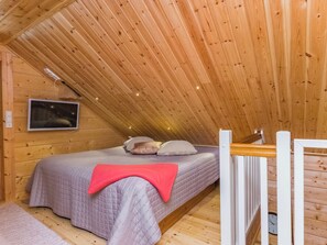 A wooden interior with a bed, a television mounted on the wall, and a wooden staircase. - Katariina by Interhome (Juva)