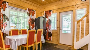 Un coin repas avec une table dressée pour six personnes, des chaises en bois, un réfrigérateur et un escalier menant à un autre niveau.