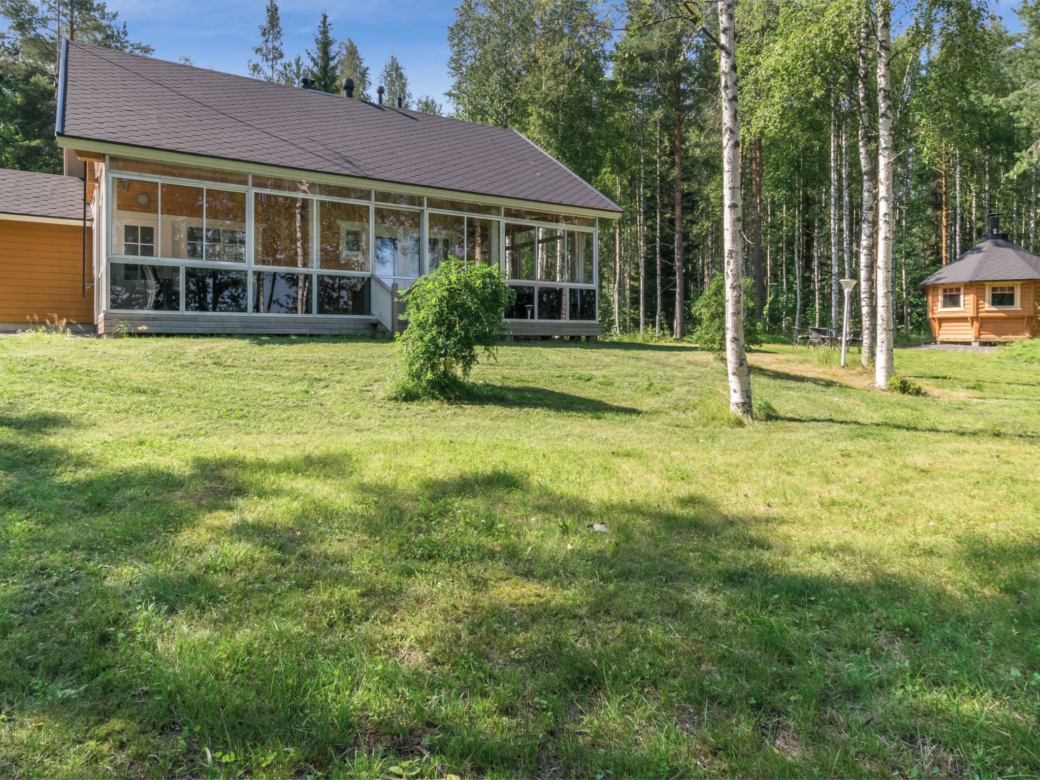 A modern house with large windows, a wooden deck, and a small garden.